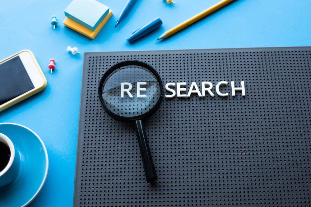 Pinboard with the word 'research' and a loupe.